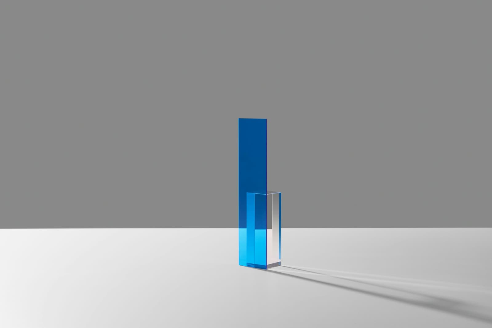 Blaue Glassäule vor grauer Wand